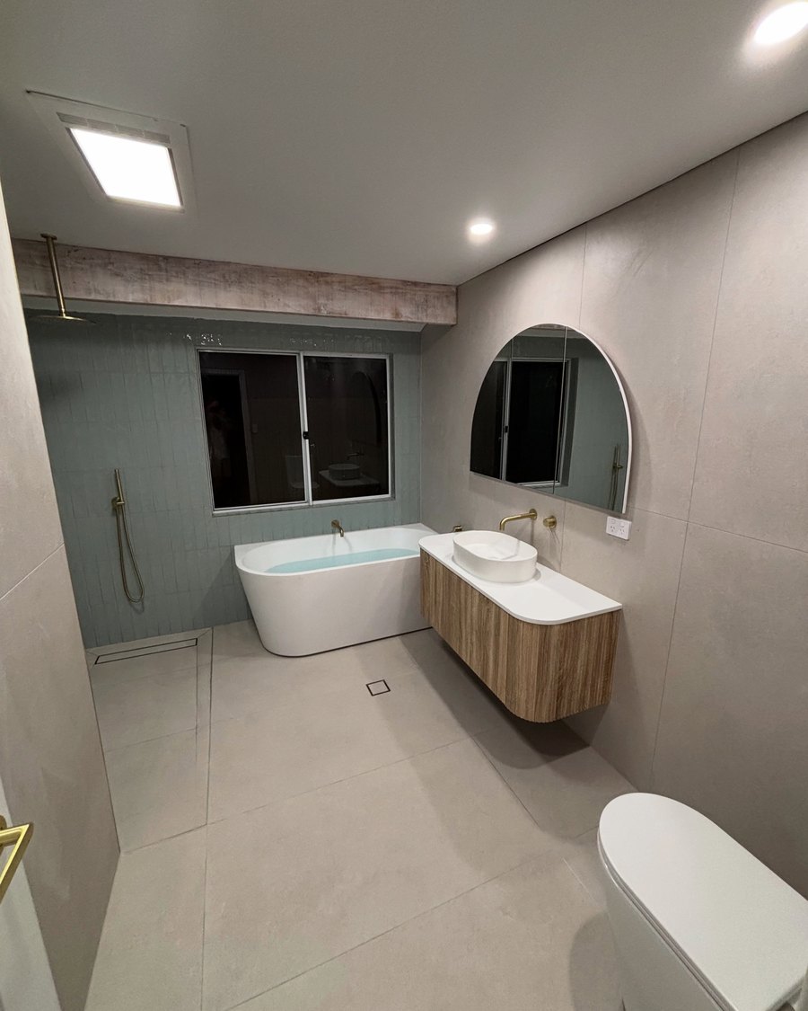 Finished bathroom with a freestanding bath, timber wall-hung vanity and arched mirror