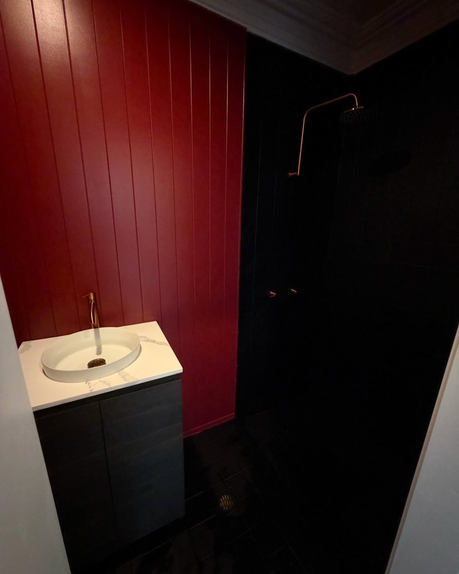 Bathroom with a red VJ panel wall, white basin and brass tapware