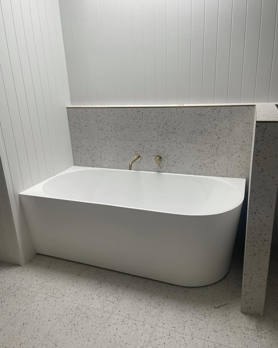 Back-to-wall bath with brass tapware and terrazzo tiles